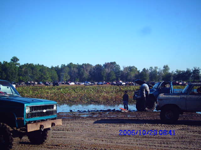 Off-road vehicles in a muddy field with trees in background. Date stamp 2006/10/29