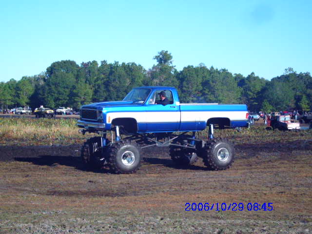 Blue and white lifted pickup truck with large tires, seen from the side
