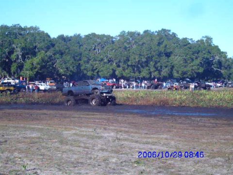 1987 Suzuki Samurai - Monster trucks compete in a mud bog event with many spectators watching.