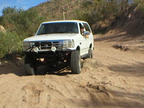 1993 Ford Bronco - White 1993 Ford Bronco navigates a sandy off-road path.