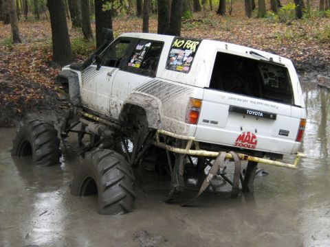 1990 Ford Bronco - Modified Toyota 4Runner deep in mud with oversized tires and "NO FEAR" sticker.
