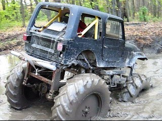 1990 Ford Bronco - This heavily modified Jeep Wrangler navigates a muddy off-road course with its oversized tires.