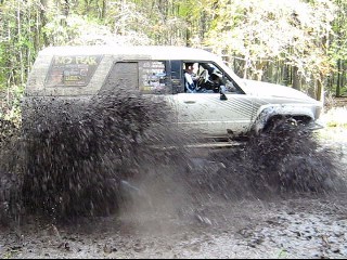 1990 Ford Bronco - An SUV navigates a muddy trail, sending mud flying everywhere.