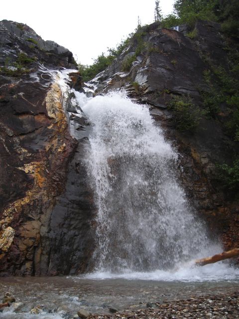 2003 Jeep TJ - A powerful waterfall plunges down a rocky mountainside, with a fallen log resting in the churning water at its base.