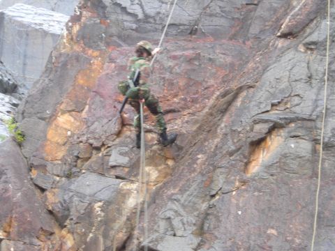 2003 Jeep TJ - A person rappels down a steep, rocky cliff face using ropes and climbing gear.