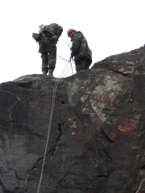 2003 Jeep TJ - Two individuals in military attire prepare for rappelling on a rocky outcrop.