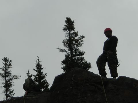 2003 Jeep TJ - Climbers prepare for an ascent on a rocky cliff face with sparse trees.