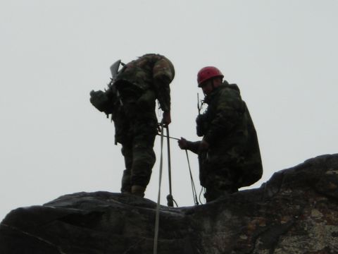 2003 Jeep TJ - Two individuals are engaged in a rappelling activity on a rocky outcrop against a cloudy sky.
