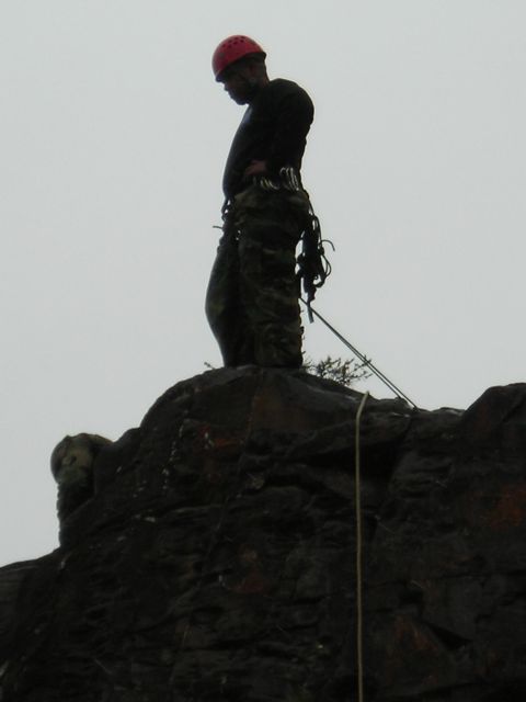 2003 Jeep TJ - A climber prepares for an ascent on a rocky outcrop under an overcast sky.