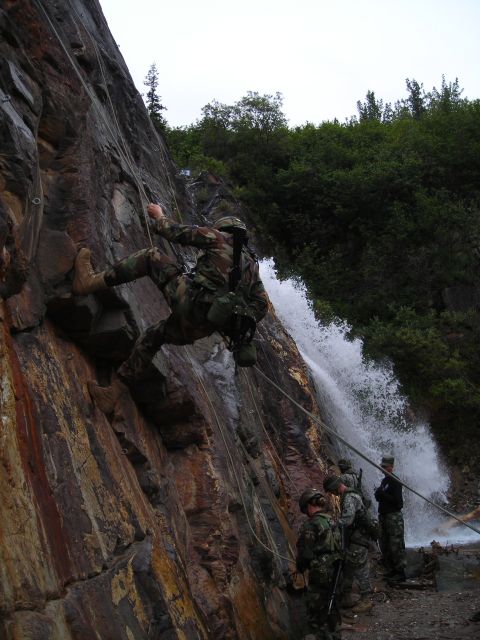 2003 Jeep TJ - Military personnel practice rappelling down a steep rock face with a waterfall cascading nearby.