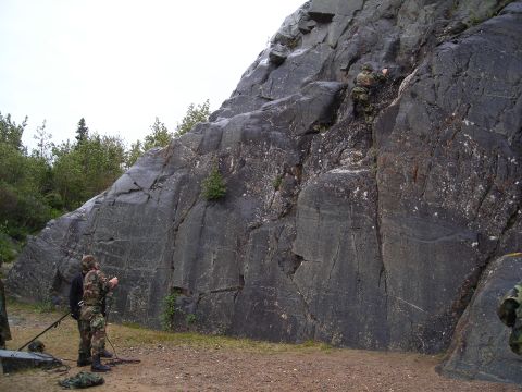2003 Jeep TJ - Two individuals in camouflage gear observe as another climbs a rocky cliff face.