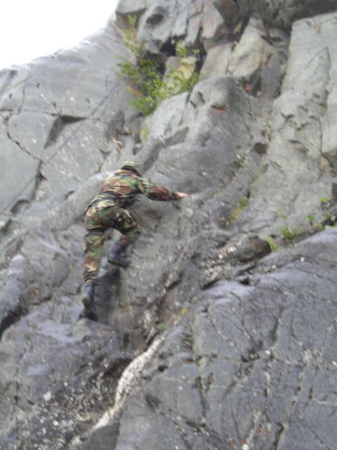 2003 Jeep TJ - A person in camouflage gear ascends a steep, rocky incline.