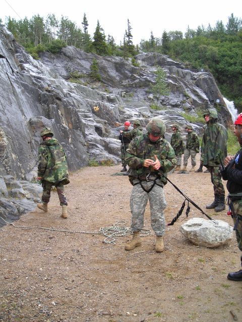 2003 Jeep TJ - Military personnel gear up for a rappelling exercise near a waterfall and wooded area.
