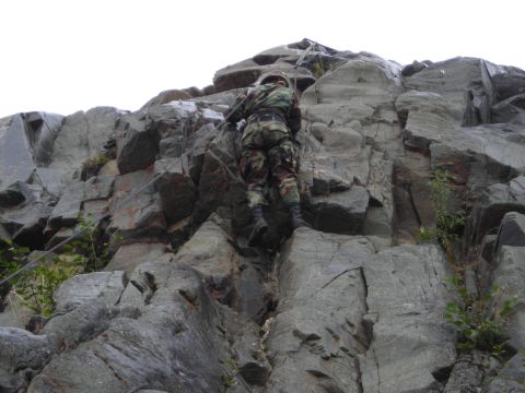 2003 Jeep TJ - A soldier scales a challenging rock formation, demonstrating climbing skills.