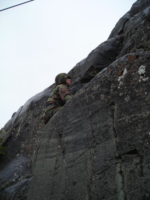 2003 Jeep TJ - A person in camouflage and helmet ascends a rock formation.