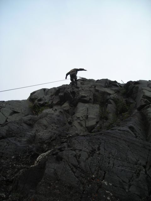 2003 Jeep TJ - A rock climber is ascending a steep cliff face, secured by a rope.