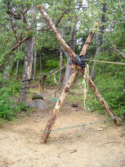 2003 Jeep TJ - A makeshift tripod structure, constructed from logs and secured with ropes, stands in a forest clearing.