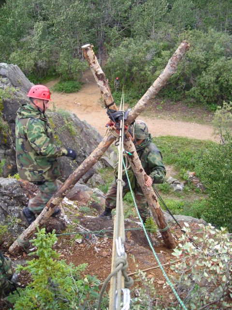 2003 Jeep TJ - Personnel prepare ropes and a wooden anchor system on a steep, wooded incline for an operation.