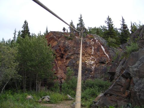 2003 Jeep TJ - A rope spans across a rocky, wooded landscape where two individuals are visible on a cliff edge.