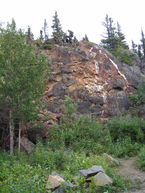 2003 Jeep TJ - People are gathered on a rocky hillside with trees and vegetation.