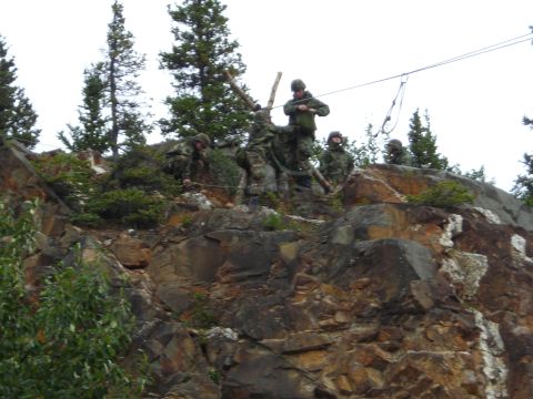 2003 Jeep TJ - Military personnel practice rappelling down a steep, rocky incline under an overcast sky.