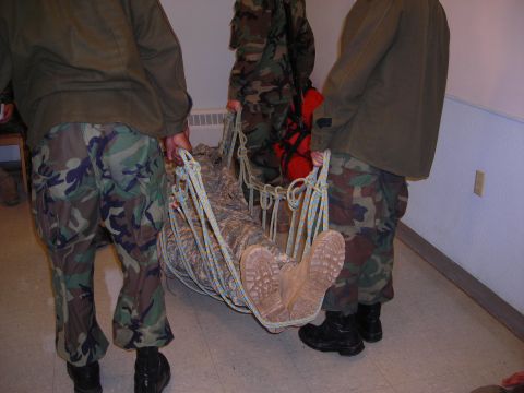 2003 Jeep TJ - Military personnel transport an individual using a stretcher net.