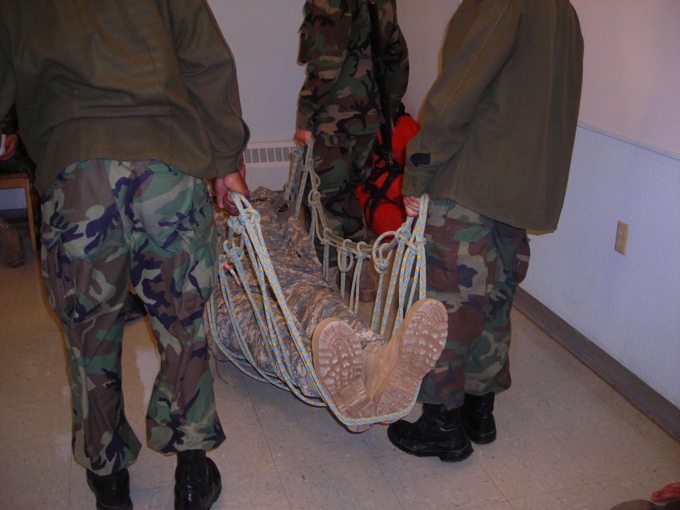 Soldiers in camouflage carrying a person in a stretcher