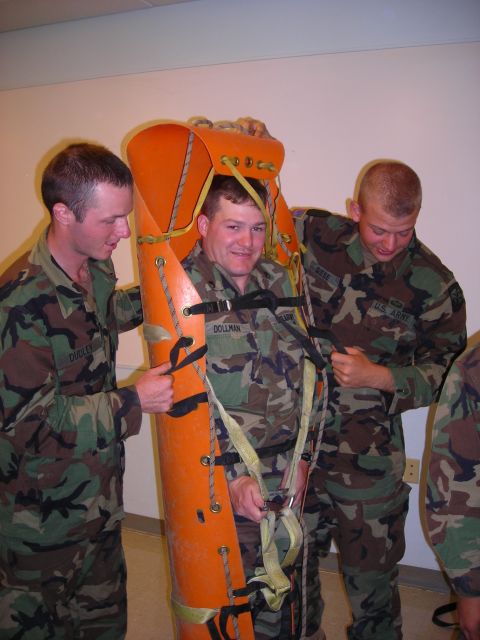 2003 Jeep TJ - Military personnel practice with a stretcher, securing a person inside for transport.