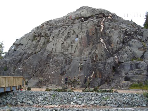 2003 Jeep TJ - Military personnel engage in rock climbing and rappelling exercises on a steep, rocky incline.