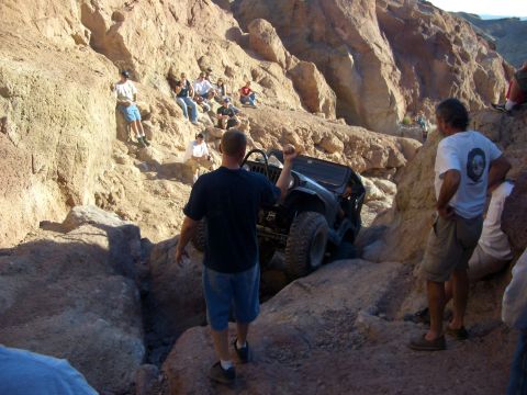 1985 Ford Bronco - A group of spectators watches an off-road vehicle ascend a challenging rocky terrain.