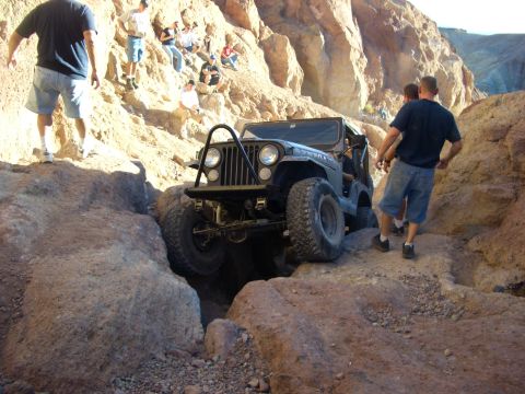 1985 Ford Bronco - A Jeep Wrangler tackles a challenging off-road trail in a desert canyon.