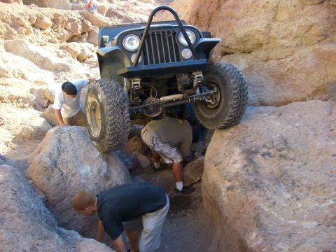 1985 Ford Bronco - Jeep CJ-7 carefully maneuvers over large rocks on a challenging off-road course.