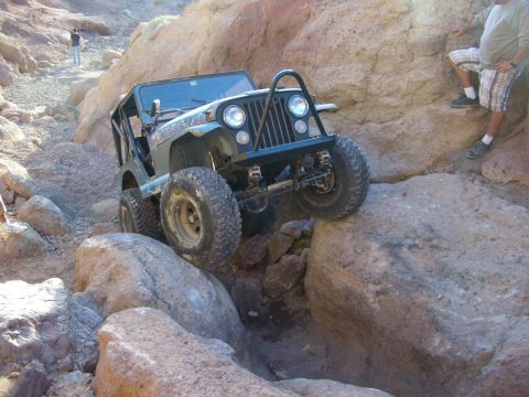 1985 Ford Bronco - Jeep Wrangler navigates a challenging rocky off-road path.
