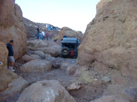 1985 Ford Bronco - Off-road vehicle carefully maneuvers through a challenging rocky terrain in a desert canyon.