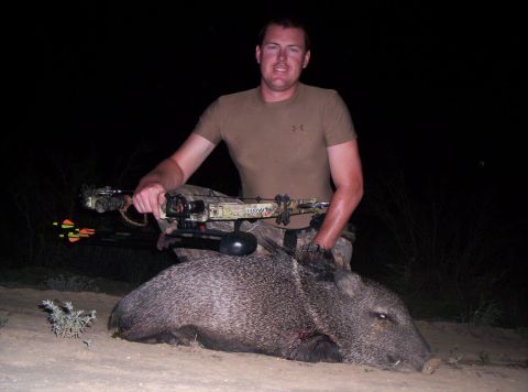 2005 BMW 3 Series - A hunter poses with his javelina kill at night, holding a crossbow.
