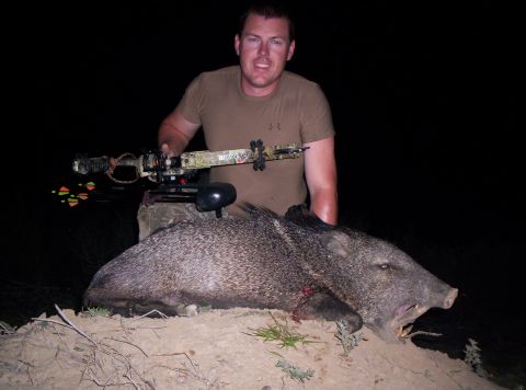 2005 BMW 3 Series - A hunter displays a javelina he has killed, holding a crossbow over the animal.