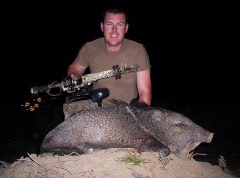 2005 BMW 3 Series - A man poses with a javelina he hunted with a bow and arrow.