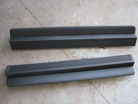 2003 Ford Crown Victoria - Two black plastic running boards with ribbed texture are shown lying on a concrete surface.