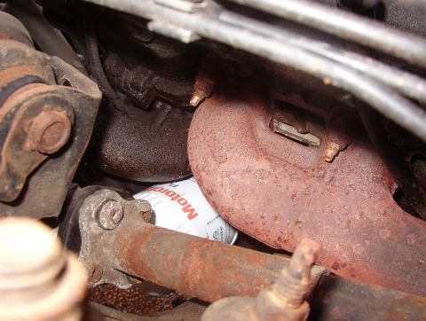 1999 Ford Crown Victoria - Close-up view of an engine's oil filter and exhaust manifold, showing signs of rust.