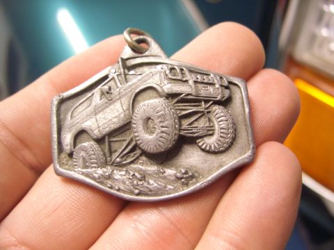 1974 Ford Bronco - This metal charm features a detailed relief of an off-road vehicle, likely a representation of a classic SUV.