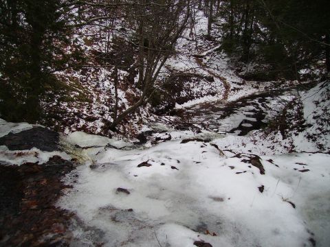 2000 Chevrolet Tahoe - A winter scene with snow and ice covering the ground and a creek flowing through a wooded area.