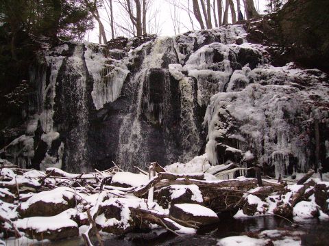 2000 Chevrolet Tahoe - A partially frozen waterfall cascades down a rocky cliff face, surrounded by snow and bare trees.