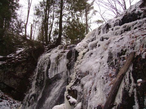 2000 Chevrolet Tahoe - A partially frozen waterfall cascades down a rocky slope surrounded by trees in a winter landscape.