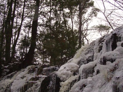2000 Chevrolet Tahoe - A frozen waterfall cascades over rocks, surrounded by trees and ice. The scene captures a winter landscape.