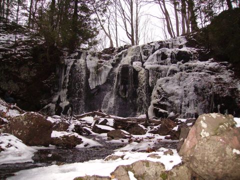 2000 Chevrolet Tahoe - A partially frozen waterfall cascades over rocks, surrounded by snow-covered trees and boulders.