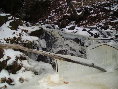 2000 Chevrolet Tahoe - A frozen waterfall with logs and snow covers the rocks, with the Supermotors.net logo visible in the lower right corner.