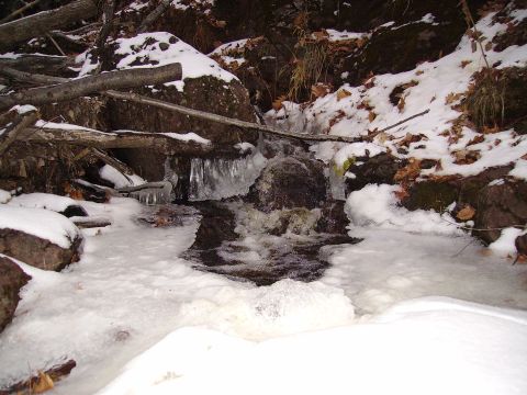 2000 Chevrolet Tahoe - A frozen stream flows over rocks surrounded by snow and fallen logs, with the SuperMotors logo visible at the bottom right.
