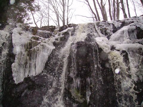 2000 Chevrolet Tahoe - A partially frozen waterfall cascades over dark rocks, with icicles forming on the sides.