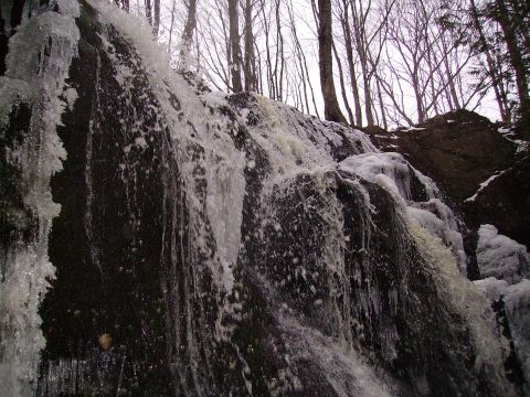 2000 Chevrolet Tahoe - A partially frozen waterfall cascades down rocks, surrounded by trees under an overcast sky.
