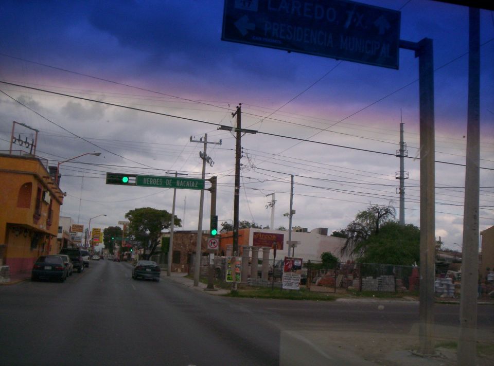 Street scene with cars, traffic lights, and signs under a cloudy sky